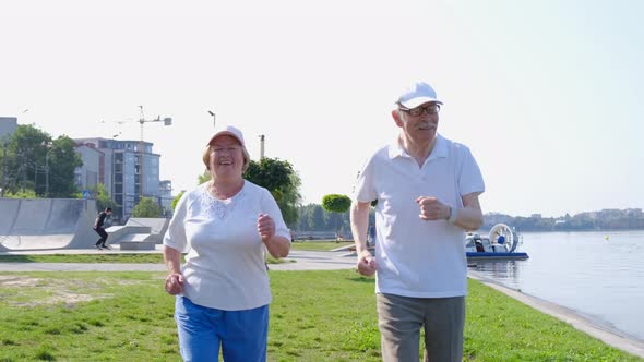 Grandparents do a morning workout by the lake. Older people run to regain energy.