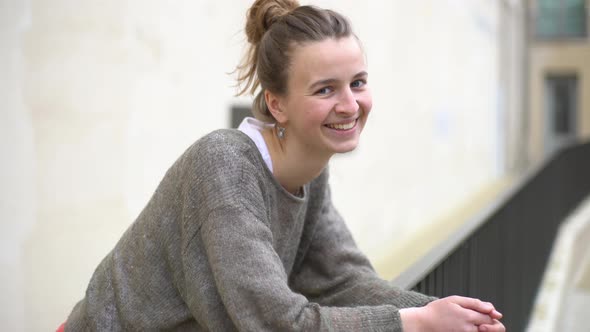 Young woman leaning against railing, smiling and laughing