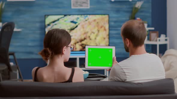 Couple Relaxing on Sofa Looking at Social Media Video Content Using Digital Tablet with Green Screen