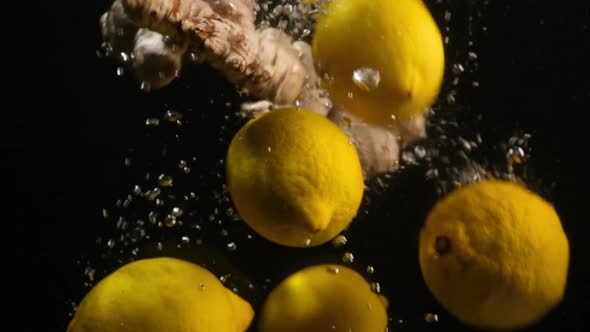 Lemon and ginger floating in water. Fresh yellow lemons falling into water with bubbles