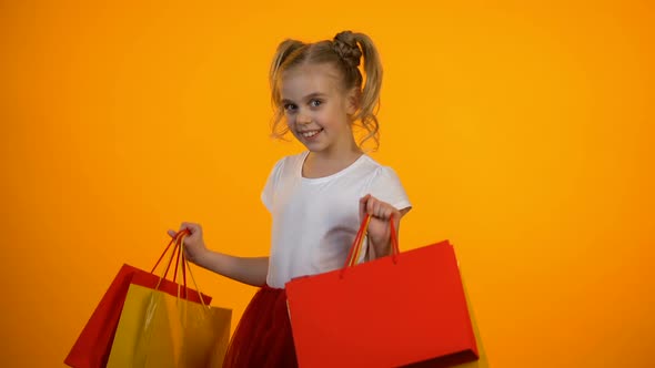 Adorable Little Girl Showing Shopping Bags, Discounts and Sales, Black Friday