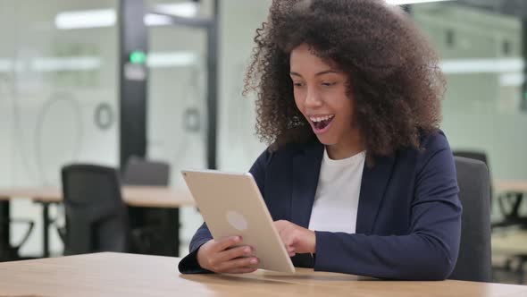 Excited African Businesswoman Celebrating Success on Tablet