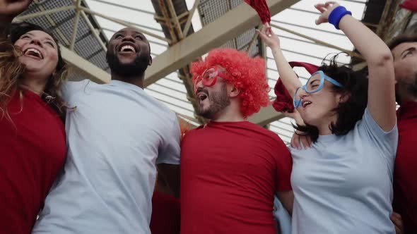 Group of People Celebrating Together the Victory of Their Soccer Team Jumping and Hugging While