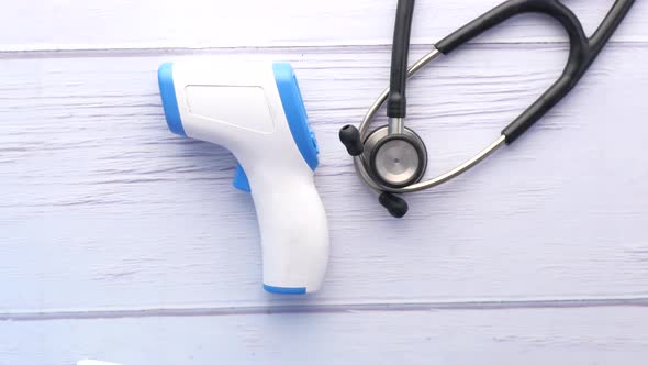 Putting Surgical Masks Thermometer and Hand Sanitizer on Wooden Table