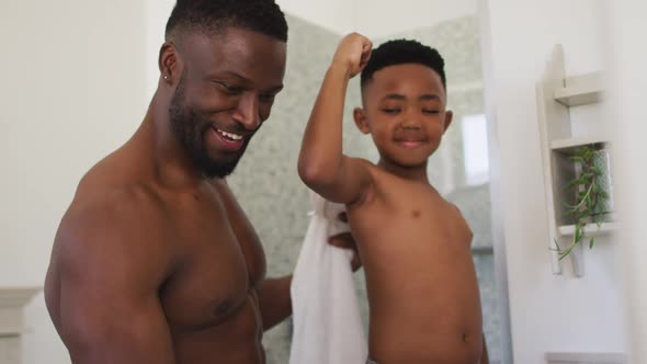 African american father and son flexing their muscles in mirror taking selfie together