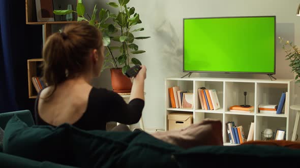 Woman Watching TV with Green Screen in Living Room Back View