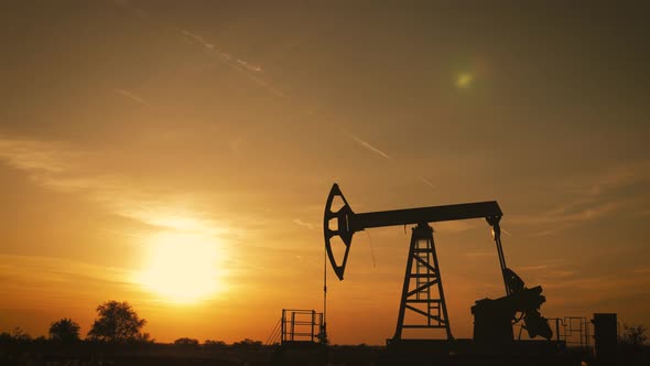 Silhouette of Working Oil Pump From Oil Field at Sunset. The Industrial Equipment