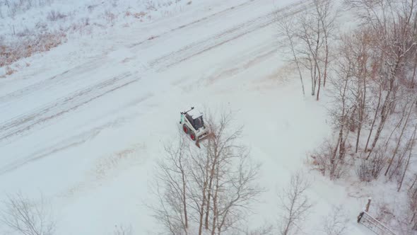 Clearing snow on a rural property with a wheeled bobcat