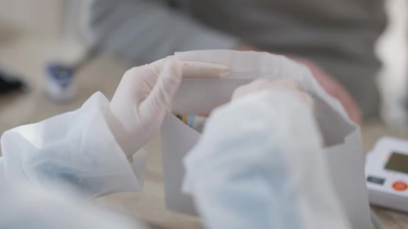 Closeup of Female Hands in Medical Gloves Counting Money in Envelope