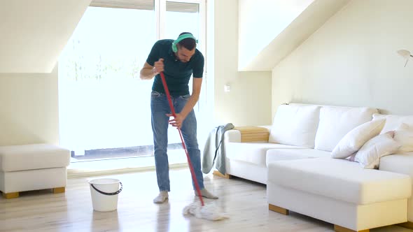 Man in Headphones Cleaning Floor By Mop at Home 19