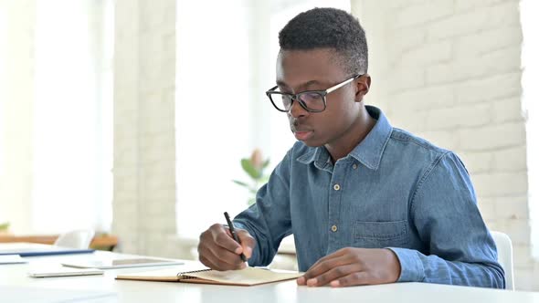 Serious Young African Man Doing Paperwork in Office