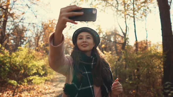 Teenage Girl Is Photographing Herself By Smartphone in Autumn Woodland