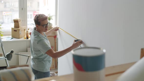 Woman Measuring Wall while Renovating Room