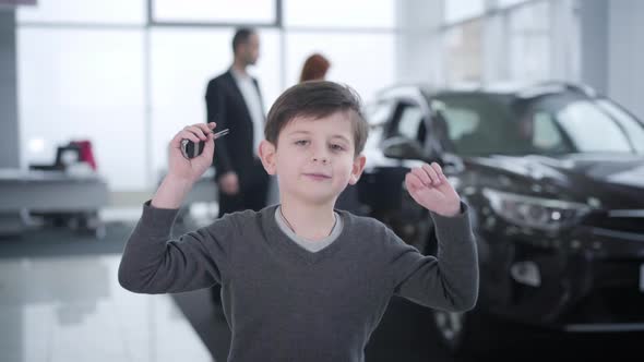 Portrait of Happy Little Caucasian Boy Jumping in Showroom Holding Car Keys