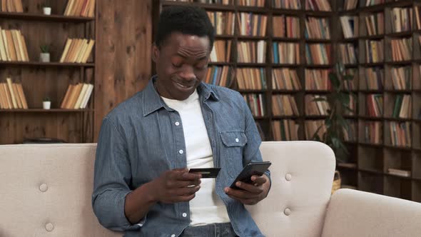 Cheerful African Man in Casual Clothing with Smartphone Make Online Payment Shopping with Credit