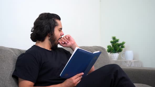 Sleepy and tired Indian man reading a book late at night