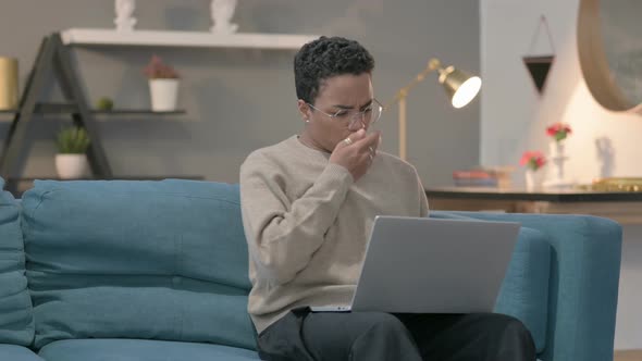 African Woman with Laptop Coughing on Sofa