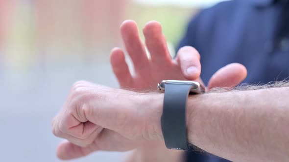 Outdoor Close Up of Hands of Middle Aged Man Scrolling on Smartwatch