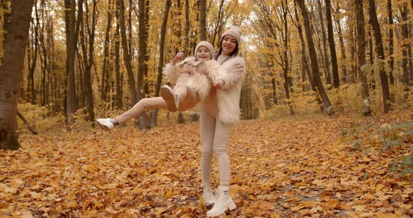 Happy Woman with Little Daughter in Autumn Park