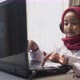 a little girl wearing red hijab typing on laptop with headphone - VideoHive Item for Sale