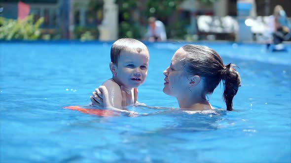 Cute Little Baby Boy and His Mother Having a Swimming Lesson in the Pool. Mom or Nanny Coach Holds