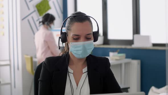 Worker Wearing Medical Face Mask and Headphone Discussing with Partners Into Microphone