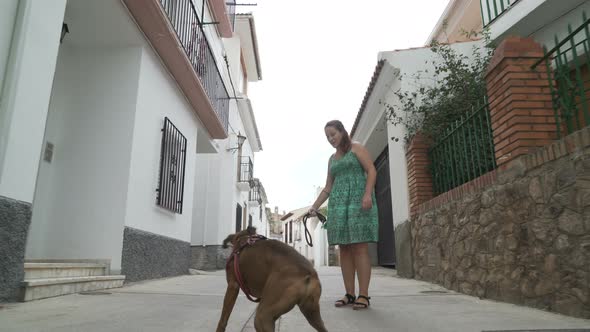 happy woman playing with boxer dog in the street