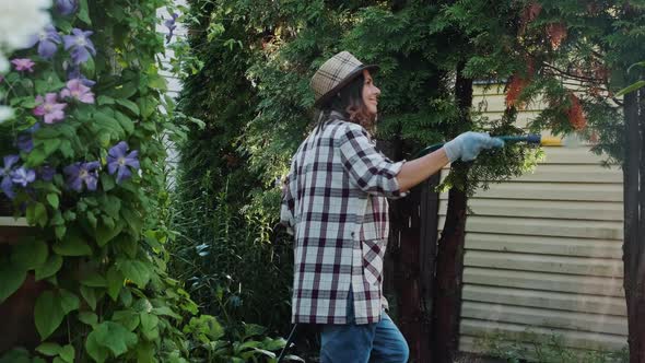 Woman Watering Plants in Garden Using Garden Hose