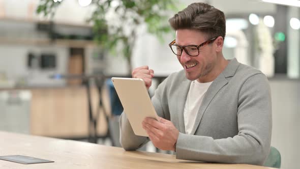 Excited Middle Aged Man Celebrating Success on Tablet