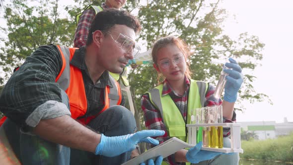 Ecologist and assistants collecting samples of factory wastewater in a test tube