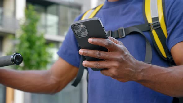 Close Up Afroamerican Man Courier Food Delivery Uses Smartphone in Blue Uniform