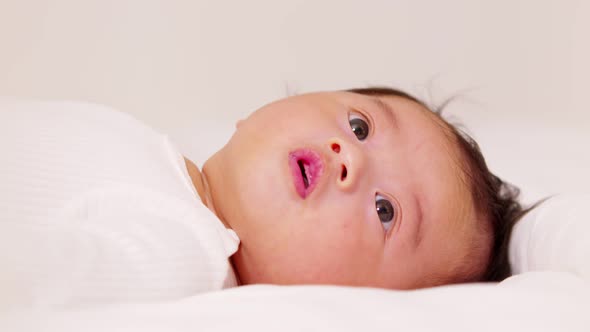 happy newborn baby lying on a white bed and blanket comfortable and safety