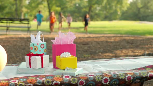 Children running to birthday presents on picnic table