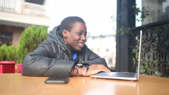 Smiling Happy African Black Shorthaired Woman Student in Black Down Jacket with Blue Headphones Have