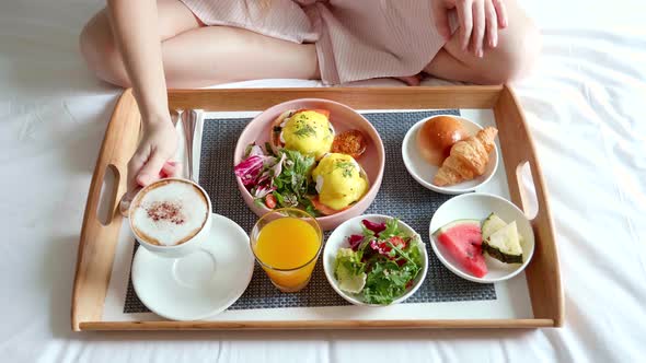 Woman Hand Puts Cup of Coffee on Breakfast in Bed Served with Salad Fresh Fruit