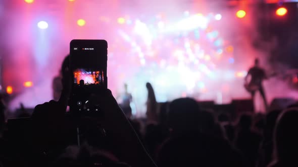 Silhouette of Woman Hands Making Video with Smartphone at Live Rock Concert. Slow Motion