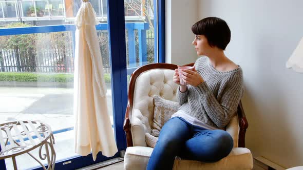 Woman looking through window while having coffee