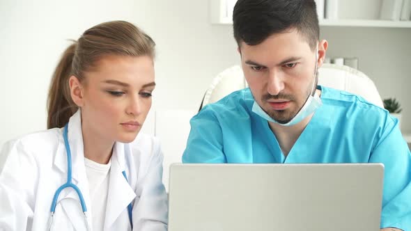 Team of Doctors Discuss Patients Diagnosis at Laptop in Clinic