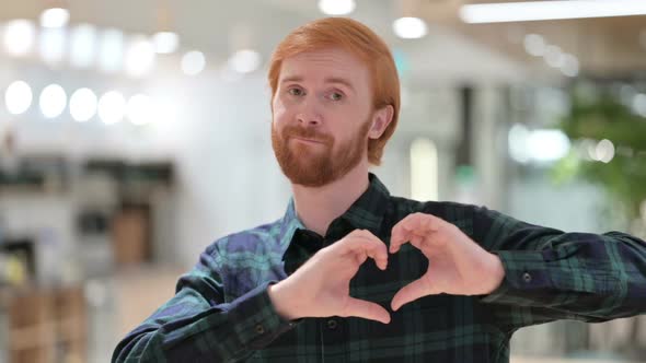 Portrait of Beard Redhead Man Making Heart Sign By Hand