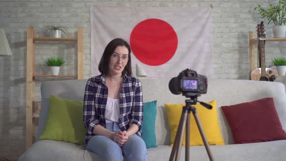 Young Woman Blogger in the Shirt on the Background of the Flag of Japan Records a Video