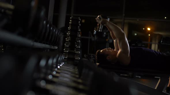 Purposeful Athlete Performing Dumbbell Pullovers, Lying on Bench, Chest Exercise