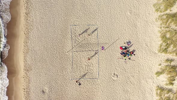 AERIAL: Volleyball Match with Long Shadows of Players on a Sand