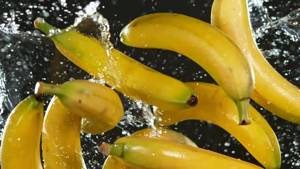 Super Slow Motion Shot of Flying Fresh Bananas and Water Side Splash Isolated on Black at 1000 Fps