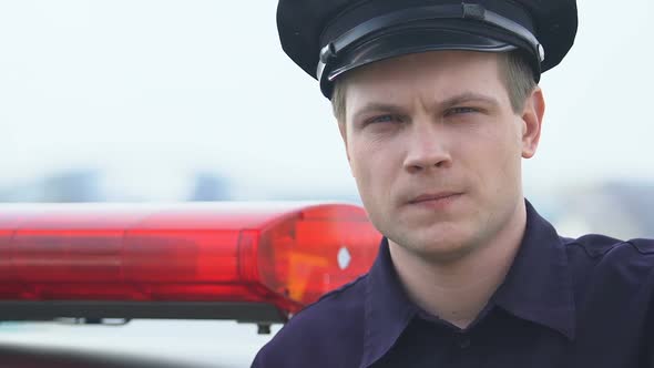 Serious Patrolman in Hat Standing Near Squad Car and Looking to Camera, Enforcer