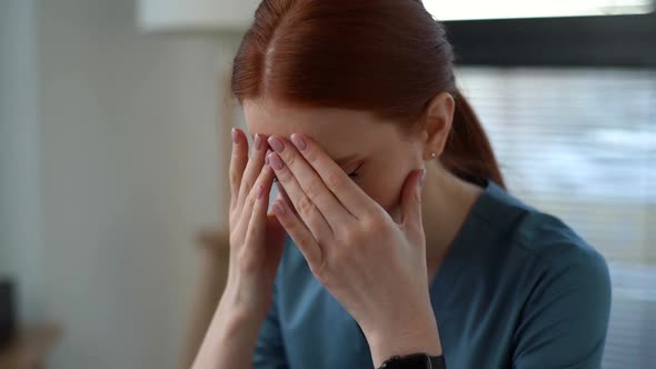 Closeup Face of Exhausted Frustrated Young Female Doctor in Blue Medical Uniform Massaging Temples