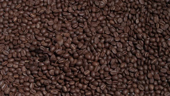 Freshly roasted coffee beans or coffee grains fall on a wooden table on a brown background at cafe.