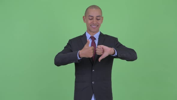 Confused Bald Multi Ethnic Businessman Choosing Between Thumbs Up and Thumbs Down