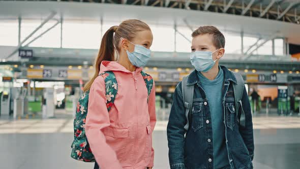 Happy Little Boy and Girl Wearing Protective Medical Masks Walking at Airport Building Talking and