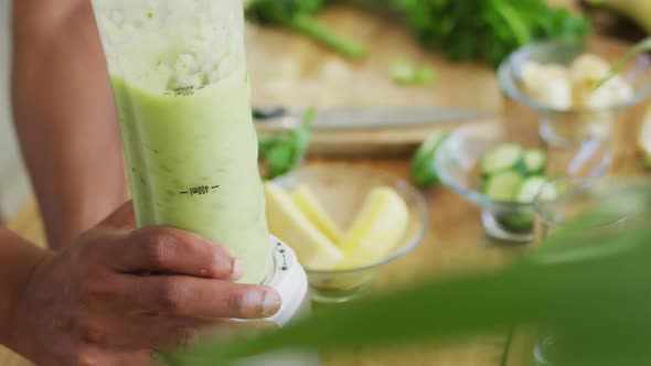 Fit african american man cooking, preparing healthy green smoothie