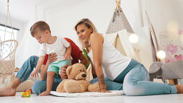 Little Boy Playing with His Father and Pregnant Mother at Home Family Concept